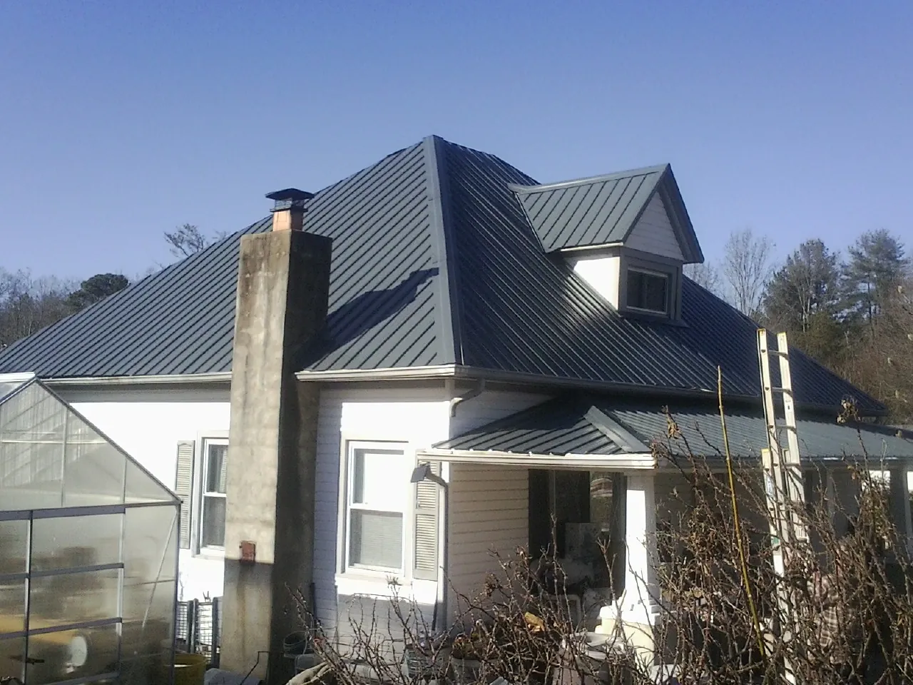 Dark blue standing seam metal roof on a white farmhouse with dormer — Slate & Tile Roof Repair by Roofing Brothers in Rockwall