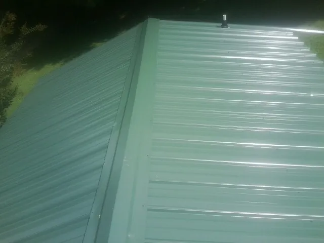 New green metal panels meeting at the ridge of a roof — Flat Roof Repair work by our crew in Rockwall