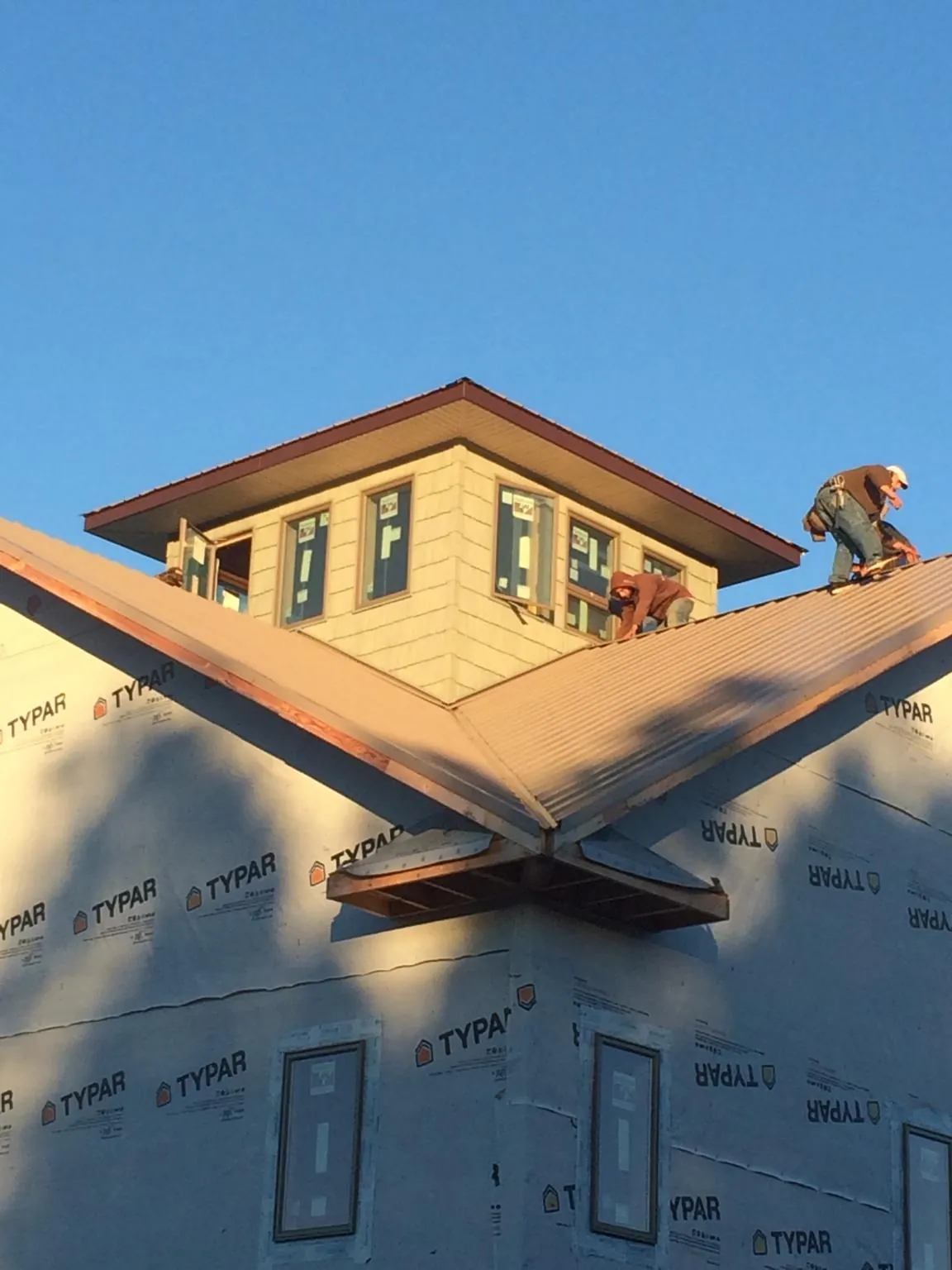 Roofers working around a rooftop cupola on a new metal roof at sunset — Roof Waterproofing in Rockwall by Roofing Brothers